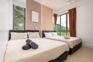 two beds in a bedroom with large windows at Serene Japandi Family Retreat 2-6 pax& Sunrise View in Brinchang
