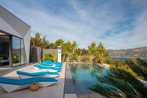 una fila di sedie a sdraio blu sedute accanto a una piscina di Villa Aqua Majestic Diamond Sumptuous 5 Bedroom Villa Magnificent Adriatic Seaviews Korcula a Korčula