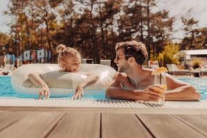 Ein Mann und ein Mädchen in einem Schwimmbecken in der Unterkunft Hotel Linea Mare in Pobierowo