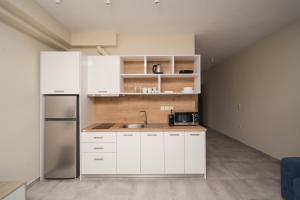een keuken met witte kasten en een roestvrijstalen koelkast bij Octo Villas Complex in Iraklitsa