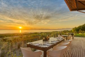 a dining table and chairs on a deck with the sunset at Grootbos Private Nature Reserve in Gansbaai