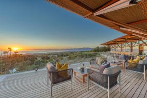 a deck with chairs and tables and the sunset at Grootbos Private Nature Reserve in Gansbaai