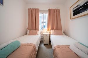 カレタ・デ・ファマラにあるFamara Home Beachのピンクのカーテンが備わるドミトリールームのベッド2台