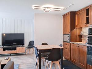 une cuisine avec une table et des chaises et une télévision dans l'établissement Week End 3, à Verbier
