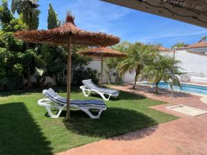 Dos sillas y una sombrilla junto a una piscina. en Azafama Buena, en Chiclana de la Frontera