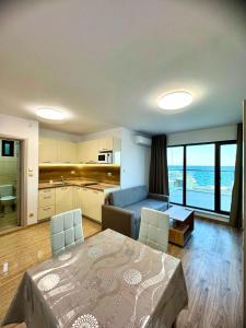 a kitchen and a living room with a table and chairs at Cabacum Pleasure Beachfront Apartments in Varna City