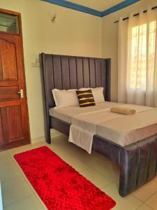 a bedroom with a large bed and a red rug at Ocean Breeze Apartments,Shanzu in Mombasa