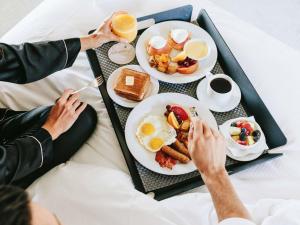two people sitting in bed with breakfast foods and drinks at Fairmont Banff Springs in Banff