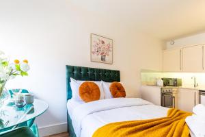 a bedroom with a large bed with orange pillows at Kensington Luxury Suites in London