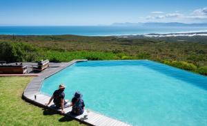 two people sitting next to a large swimming pool at Grootbos Private Nature Reserve in Gansbaai