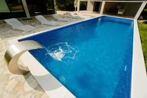 a blue swimming pool with chairs in a yard at Villa Aurea in Neum