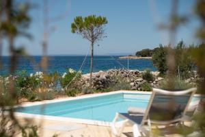a swimming pool with two chairs and the ocean at Terra Park Phalaris in Novalja
