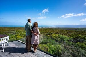 a couple standing on a deck looking out at the ocean at Grootbos Private Nature Reserve in Gansbaai
