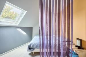 a bedroom with a bed and a curtain at Le Nid Marin - A 400m de la plage in Saint-Aubin-sur-Mer