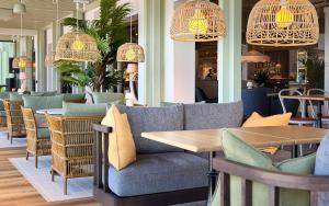 a restaurant with a couch and tables and chandeliers at Havna Hotel & Sjøbad in Tjøme +39 photos