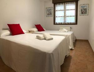 two beds with white and red pillows in a room at Playa Ribadesella Cris in Ribadesella