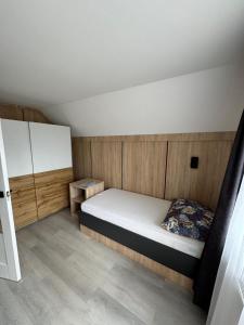 a small bedroom with a bed and wooden walls at Sóstó Suites in Nyíregyháza