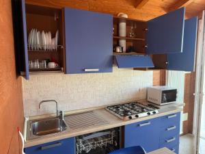 a kitchen with blue cabinets and a sink and a stove at Bungalow Casa Celeste Sul Mare in Cesenatico