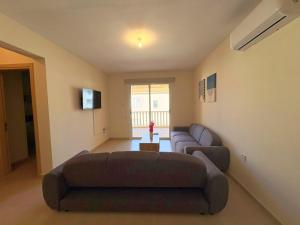 a living room with a couch and a tv at Sunrise Palette Suites in Larnaca
