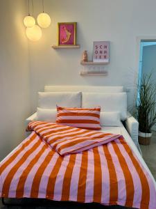 a bed with an orange and white striped comforter at Sievershof Strandbar in Wietzendorf +22 photos