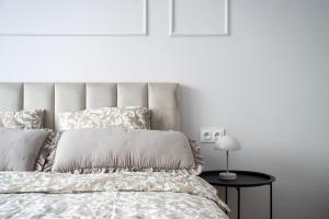 a white bedroom with a bed and a table with a lamp at ApartGo! P in Radom