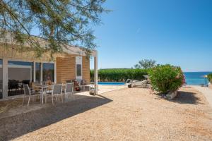 a house with a table and chairs and the ocean at Terra Park Phalaris in Novalja