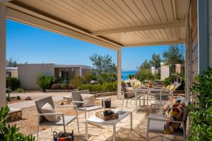 an outdoor patio with chairs and tables and awning at Terra Park Phalaris in Novalja