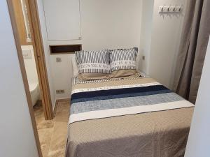 a small bedroom with a bed with striped pillows at Splendide Vue Mer in Sainte-Maxime