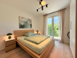 a bedroom with a bed and a large window at Suite Carpe Diem in Uhldingen-Mühlhofen