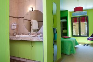 een groene badkamer met een wastafel en een spiegel bij Logis hôtel Ô en Couleur in Oucques