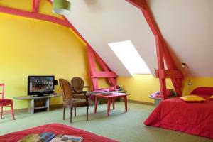 een slaapkamer met een bed en een tv in een kamer bij Logis hôtel Ô en Couleur in Oucques
