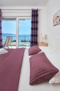 sypialnia z łóżkiem z fioletowymi poduszkami i balkonem w obiekcie Villa Mila Trogir w Trogirze