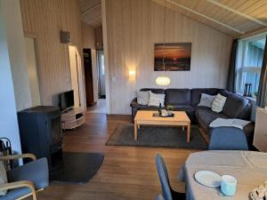 a living room with a couch and a table at 6 Personen Ferienhaus mit Sauna, Whirlpool, Kaminofen und Kanu in 2. Rheie zum See in Otterndorf in Otterndorf