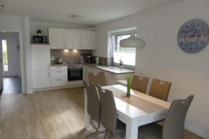 a kitchen and dining room with a table and chairs at 6 Personen Ferienhaus mit zwei Duschen und Toiletten, Sauna, Whirlpool und Kaminofen in Otterndorf in Otterndorf