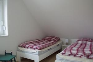 two twin beds in a room with a table at 6 Personen Ferienhaus mit zwei Duschen und Toiletten, Sauna, Whirlpool und Kaminofen in Otterndorf in Otterndorf