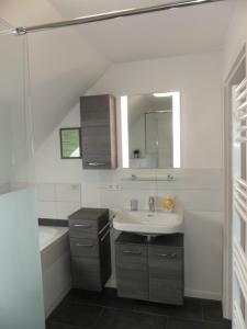 a bathroom with a sink and a tub and a mirror at 6 Personen Ferienhaus mit zwei Duschen und Toiletten, Sauna, Whirlpool und Kaminofen in Otterndorf in Otterndorf +17 photos