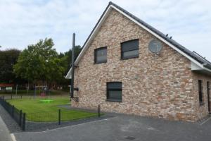 a brick building with a playground in the background at 6 Personen Ferienhaus mit zwei Duschen und Toiletten, Sauna, Whirlpool und Kaminofen in Otterndorf in Otterndorf