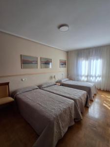a hotel room with three beds and a window at Arriondas Toyos A in Arriondas