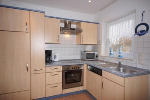 a kitchen with wooden cabinets and a sink at 5 Personen Ferienhaus mit Kaminofen in erster Reihe hinterm Deich in Otterndorf in Otterndorf