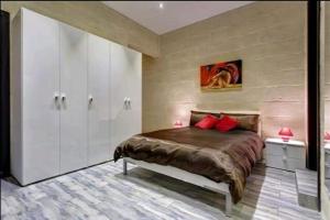 a bedroom with a bed with white cabinets and red pillows at Seafront 1 bedroom Maisonette in Kalkara