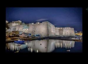 a large building with its reflection in the water at Seafront 1 bedroom Maisonette in Kalkara +6 photos