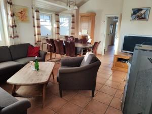 a living room with couches and a table and a television at 6 Personen Familienferienhaus mit Sauna, Whirlpool zwei Toiletten und Kaminofen in Otterndorf in Otterndorf