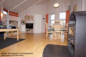 a living room with a table and a dining room at 6 Personen Ferienhaus mit privatem Bootsteg, dikekter Seelage, Kanu, Whirlpool, Sauna und Kaminofen in Otterndorf in Otterndorf