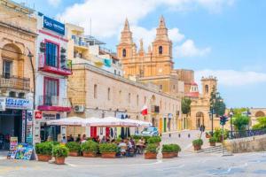 a street with people sitting under umbrellas on a city street at Modern, stylish & comfortable 3 bedroom apartment with jacuzzi and private yard with barbeque in Mellieħa