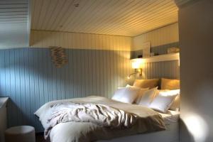 ein Schlafzimmer mit einem Bett mit weißen Laken und Kissen in der Unterkunft 8 Personen Hausboot mit Hot Tub, Sauna, Kaminofen, Klimaanlage, Lounge, Sonnendeck und Garten mit Buddelschiff direkt hinterm Deich in Otterndorf in Otterndorf