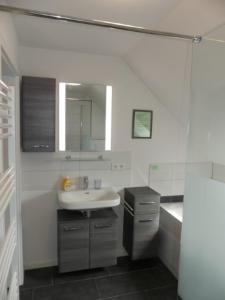 a bathroom with a sink and a tub and a mirror at 6 Personen Ferienhaus mit Sauna, Whirlpool, zwei Duschen sowie Kaminofen in Otterndorf in Otterndorf