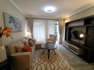 a living room with a couch and a tv and a table at Kitisuru amani gardens in Nairobi