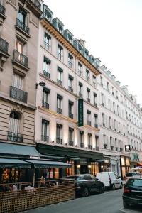 Un gran edificio blanco con coches aparcados delante. en Maison Orphée, en París