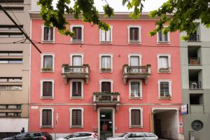 a pink building in a city with cars parked in front at Luminoso Trilocale Certosa - Mirable PM in Milan