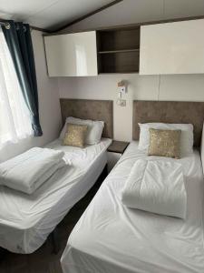 two beds in a room with white sheets and pillows at Vakantiepark Klein Strand - Luxe Chalet 4p in Jabbeke